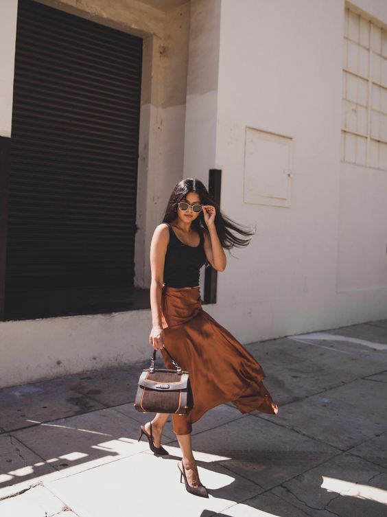 a gorgeous summer work look with a black tank top, a rust colored slip midi skirt, black slingbacks and a brown bag