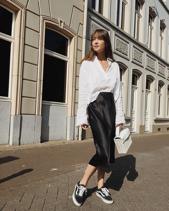 a simple black and white summer work look with a white linen shirt, a black slip midi skirt, black and white sneakers and a white wicker bag