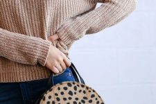 With beige loose turtleneck sweater and navy blue skinny jeans