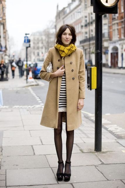 With black and white striped mini dress, beige knee length coat, white clutch, printed tights and black ankle strap platform shoes
