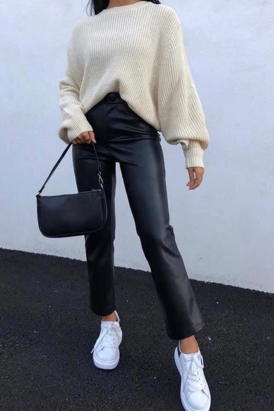 a creamy chunky knit sweater, black leather trousers, a small black bag and white sneakers for a simple winter look