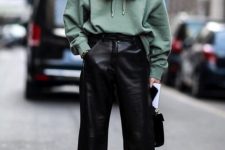 a green oversized hoodie, black straight leg leather trousers, green boots and a black bag for fall or winter