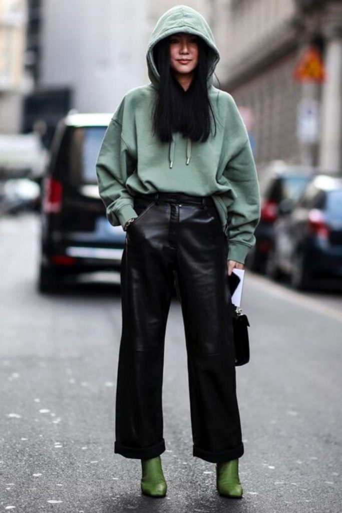 a green oversized hoodie, black straight leg leather trousers, green boots and a black bag for fall or winter