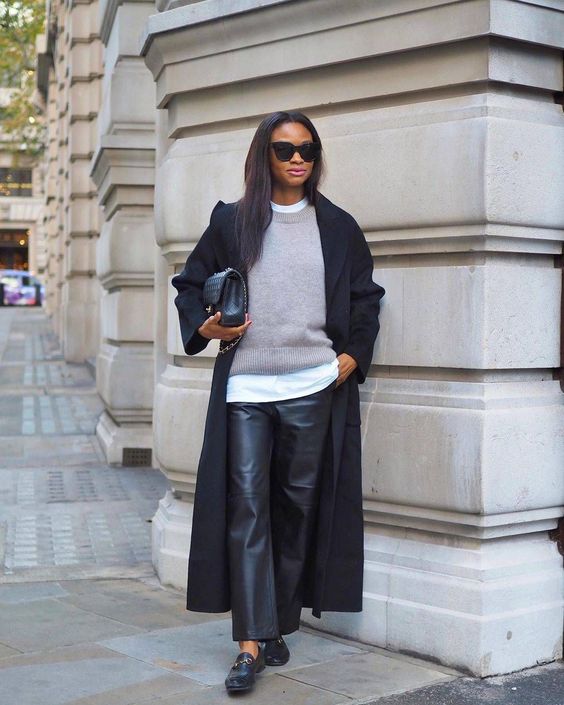 a layered monochromatic look with a white t shirt, a grey jumper, black leather trousers, black flats, a black coat and a bag
