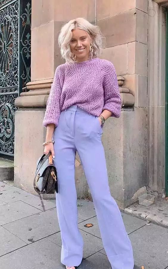 a pastel outfit with a pink patterned sweater, periwinkle flare trousers, a black bag and statement earrings