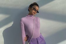 a spring outfit with a lilac ribbed turtleneck, periwinkle cargo pants, a white pearl bag