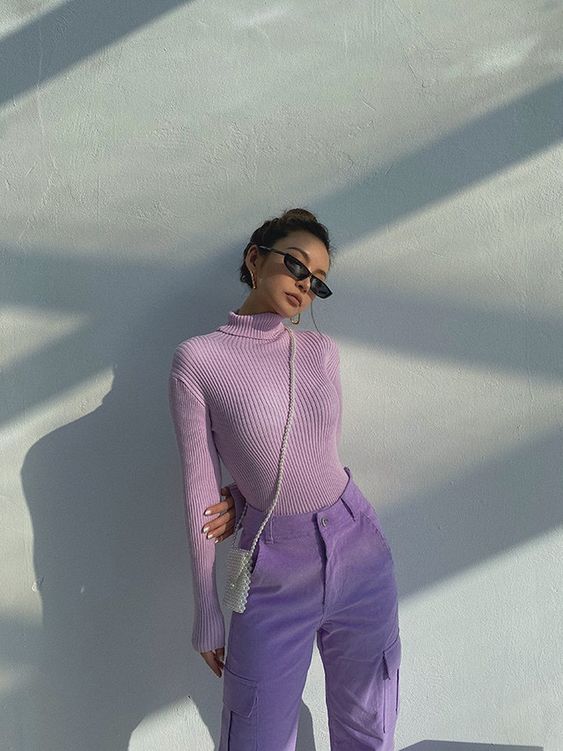 a spring outfit with a lilac ribbed turtleneck, periwinkle cargo pants, a white pearl bag
