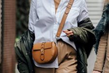 a tan turtleneck, a white shirt, tan leather trousers, a camel bag, a green puffer jacket and statement earrings