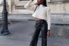 a white patterned cropped sweater, black leather high waisted trousers, white sneakers and a small white bag