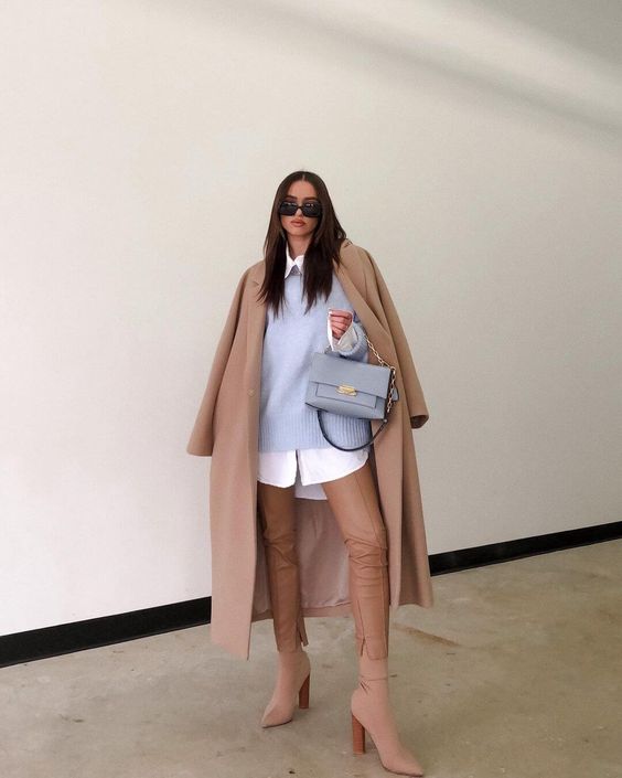 an elegant look with an oversized shirt, a pastel blue sweater, tan leather pants, matching sock boots and a coat plus a pastel bag