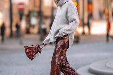 an oversized grey sweater, rust-colored sequin pants, a matching bag for a holiday look in non-typical colors
