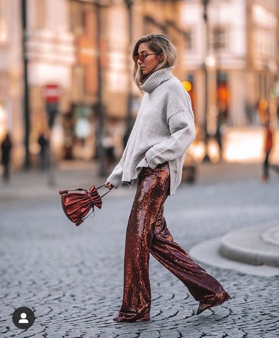 an oversized grey sweater, rust-colored sequin pants, a matching bag for a holiday look in non-typical colors