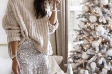 an oversized neutral chunky sweater, a silver sequin flare mini skirt and statement earrings for a festive party look