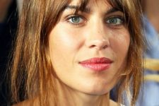Alexa Chung rocking light brunette hair with slight caramel highlights and long layered bangs for a catchy look when wearing an updo