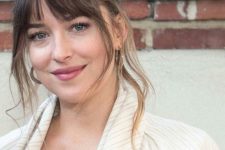 Dakota Johnson wearing her natural hair color plus some ombre highlights and bottleneck bangs looks chic