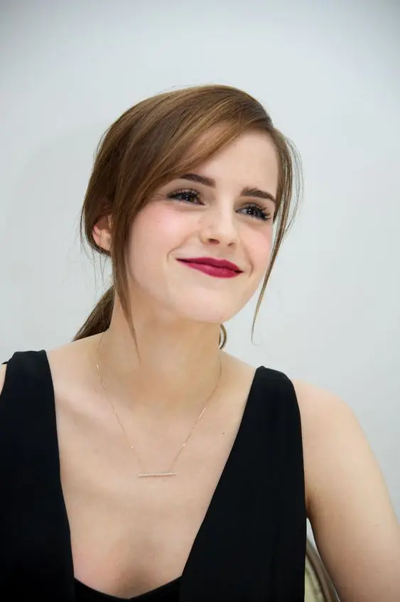 Emma Watson rocking light brunette hair in a low ponytail and side bangs looks gorgeous