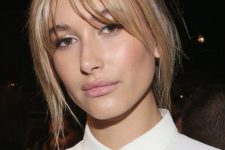 Hailey Baldwin wearing a blonde updo with layered bangs to frame the face in a delicate way and add interest to the look
