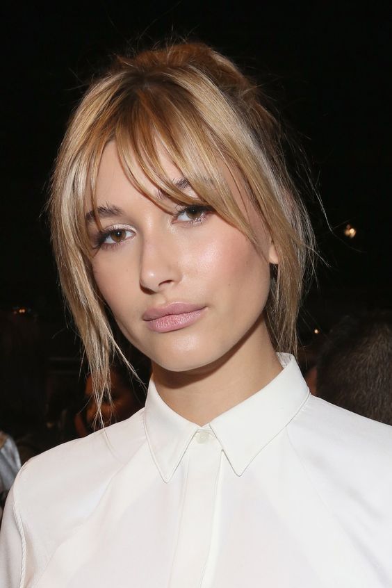 Hailey Baldwin wearing a blonde updo with layered bangs to frame the face in a delicate way and add interest to the look