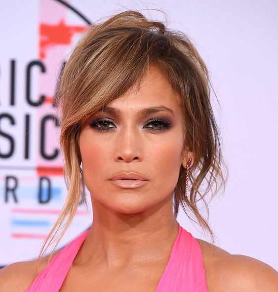 J.Lo wearing a messy updo with locks down and side-swept bangs to accent the face even more