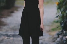 With black short sleeved mini dress, silver necklace, sunglasses and black tights
