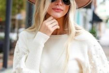With white pom pom sweater, sunglasses and jeans