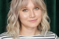 a blonde medium length hairstyle with a darker root, bottleneck bangs and waves is a lovely idea to try