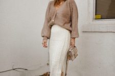 a grey cardigan tucked into a white patterned midi skirt, tan boots and a small grey bag for the transitional time