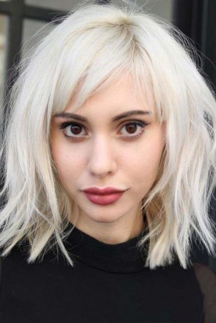a medium length shaggy icy blonde lob with side bangs is a bold statement with both the color and the look