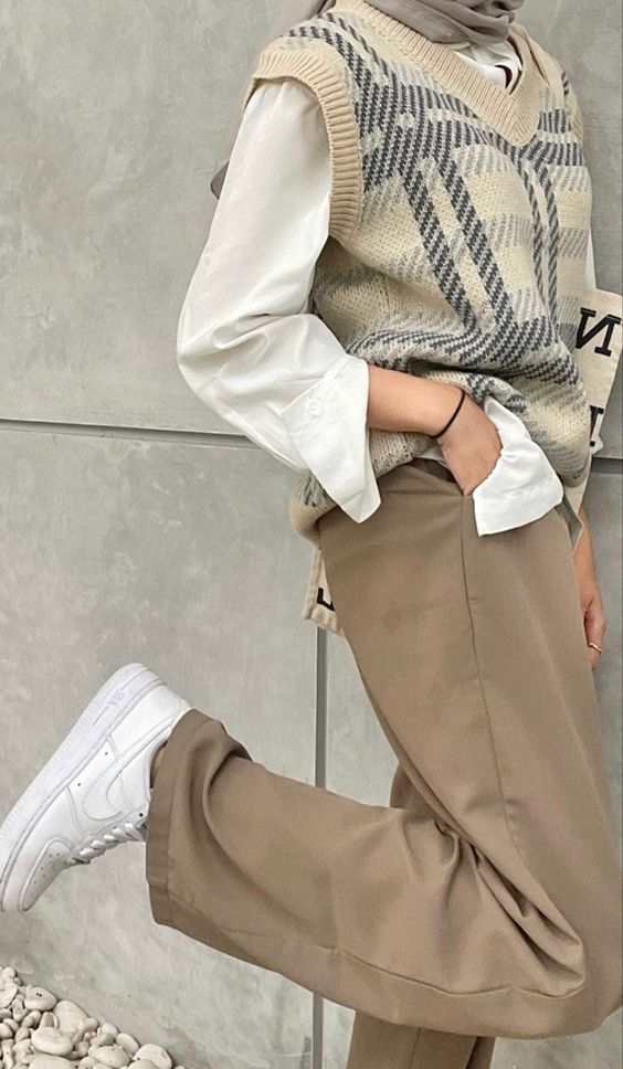 a pretty transitional outfit with a white shirt, a printed waistcoat, taupe pants and white sneakers