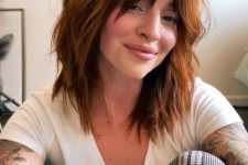 a shaggy medium-length copper haircut with messy waves and bottleneck bangs is a cool and bold idea