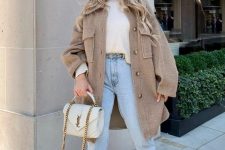 a white sweater, a tan shirt jacket, light blue jeans, blush boots, a white bag with chain for colder days