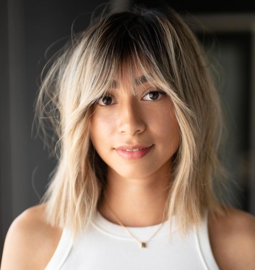 blonde hair with a darker root and texture plus outgrown looking wispy bangs for a delicate touch