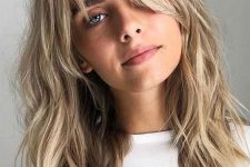 cute blonde textural long hair with waves and layered bangs that frame the face and highlight it