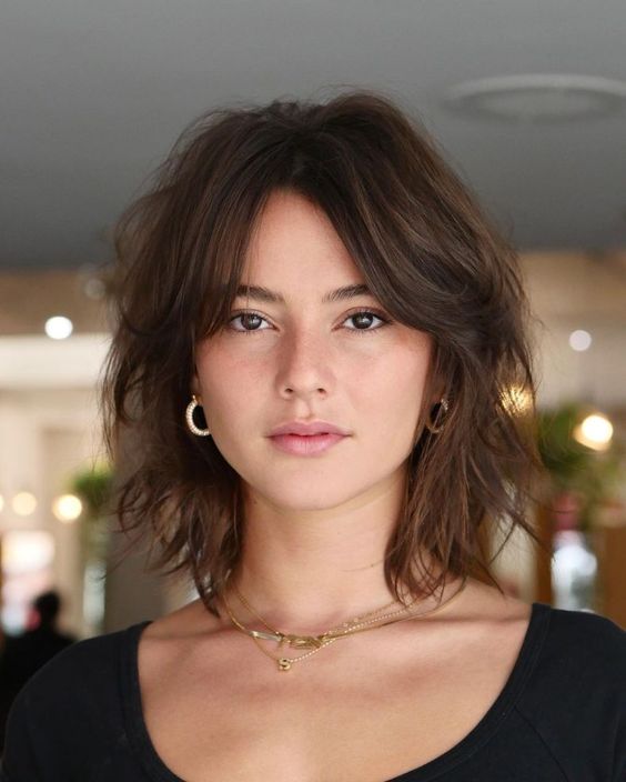 dark brown medium length hair with much texture and layered bangs almost removed from the face to highlight the eyes