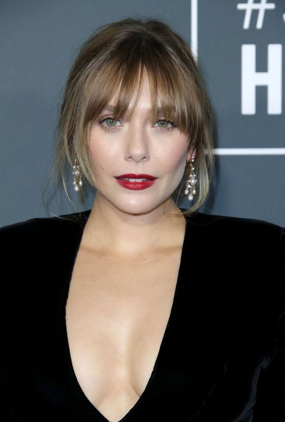 light hair with caramel highlights in an updo and with layered bangs to frame the face in a beautiful way