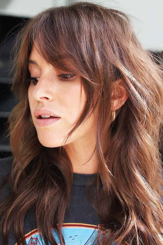 lovely long auburn wavy hair with layered curtains bangs that add texture and frame the face in a cool way