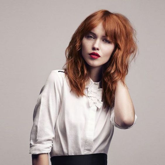 lovely textural copper red hair with waves and bottleneck bangs for a bolder look