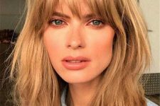 medium length messy and shaggy warm caramel blonde hair with layered bangs that that catch the eyes