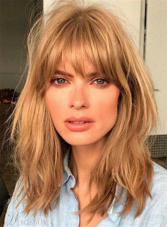 medium length messy and shaggy warm caramel blonde hair with layered bangs that that catch the eyes