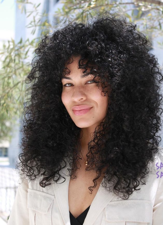 natural black curls with bottleneck bangs looks bold, chic and cool and natural hair is always on trend