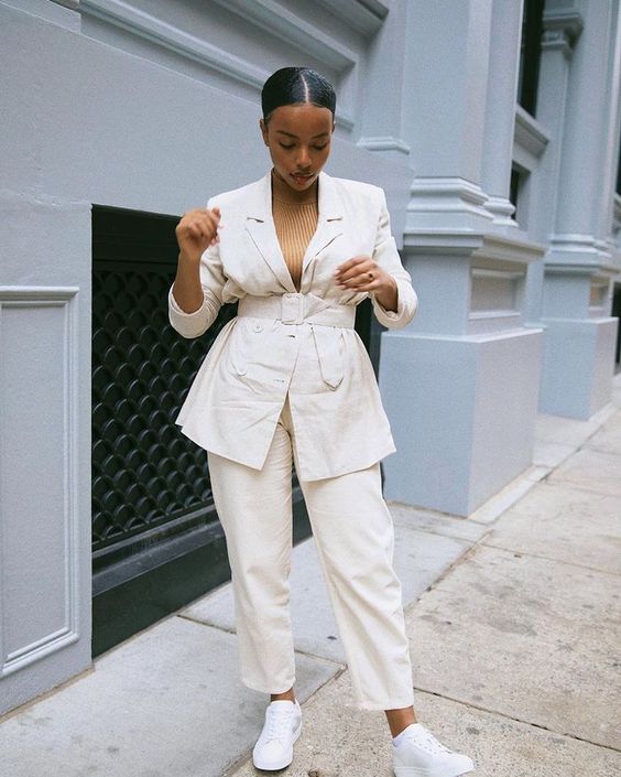 a chic and comfy outfit with a tan-colored ribbed turtleneck, a creamy linen belted blazer, creamy pants and white trainers
