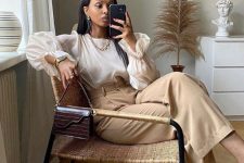 10 a refined look with a blouse with a high neckline and puff sleeves, tan high-waisted trousers, black shoes and a burgundy bag