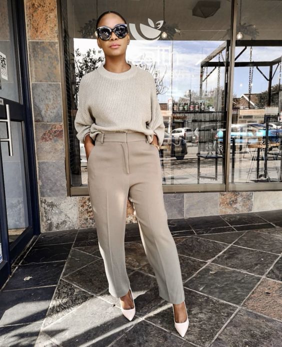 an easy and comfy outfit with an off-white ribbed jumper tucked into grey trousers, blush shoes and statement sunglasses