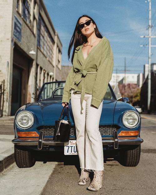 a green belted cardigan with a deep neckline, white jeans, snakeskin printed boots and a black bucket bag