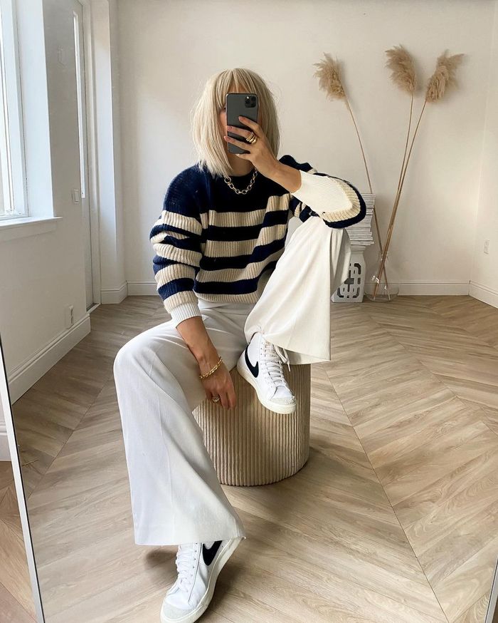 a navy and cream striped sweater, white trousers, white and black sneakers and a chain necklace for maximal comfort