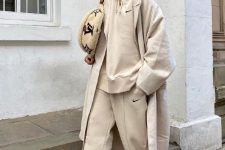 27 a neutral hoodie and sweatpants, white trainers, a neutral trench and a neutral printed bag for a comfy sporty look