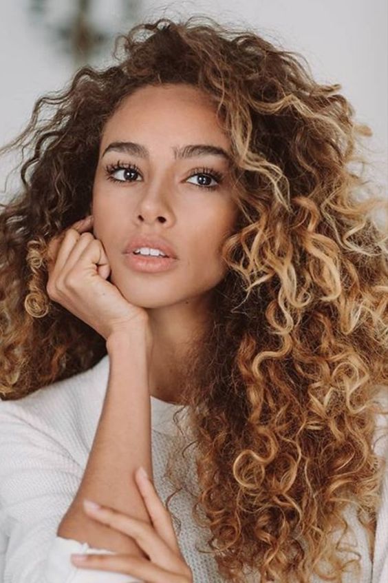 naturally curly hair with blonde balayage to make the look bolder and highlight the face at its best