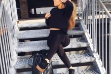 With black crop shirt, black leggings, black and beige lace up shoes and black leather bag