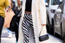 With black crop top, sunglasses, black leather mini bag, white midi coat and black and white flat boots