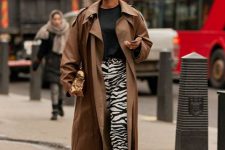 With black t-shirt, brown midi trench coat, sunglasses and white mid calf boots